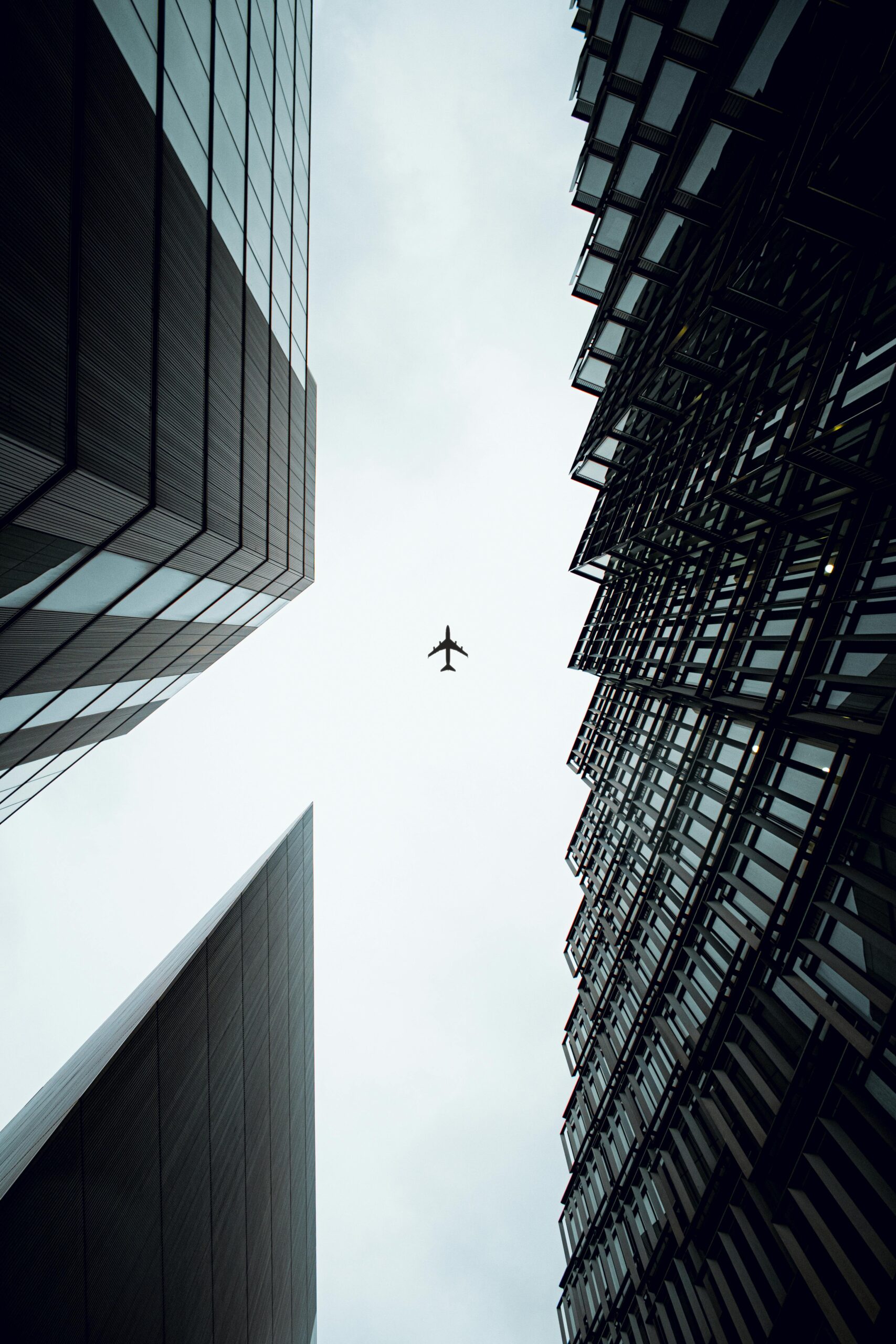 A dramatic view of an airplane flying above modern skyscrapers in London, UK.